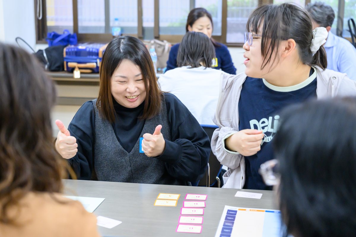 テーブルで笑顔で親指を立てる参加者